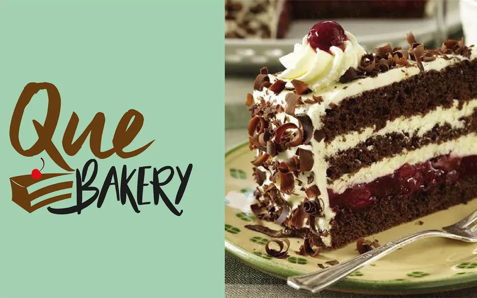 Que Bakery wordmark beside a slice of black forest cake